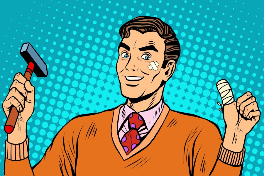 smiling man with a tie, holding a hammer in his right hand and making a thumbs up gesture with his other hand. the thumb is bandaged.